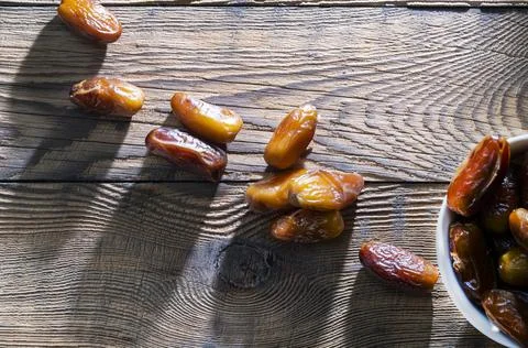 Several dry dates are lit by the setting sun on a wooden table Stock Photos