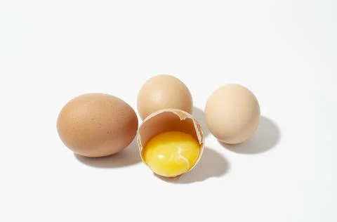 Several eggs on a white surface. one is broken Stock Photos