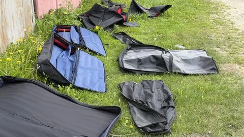 Several empty black and blue padded equipment bags scattered on green grass Stock Photos