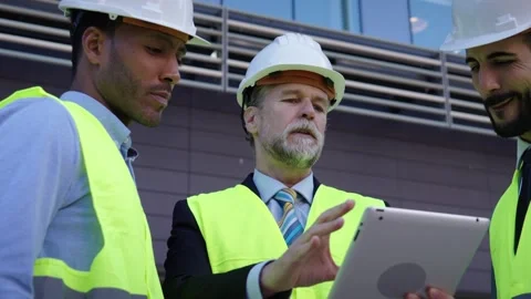 Several engineers look focused at tablet outside office building. Successful Stock Footage 256087314