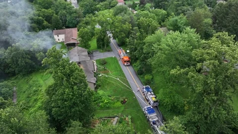Several fire trucks extinguishing burning house with rising smoke. Aerial top Stock Footage 313621523