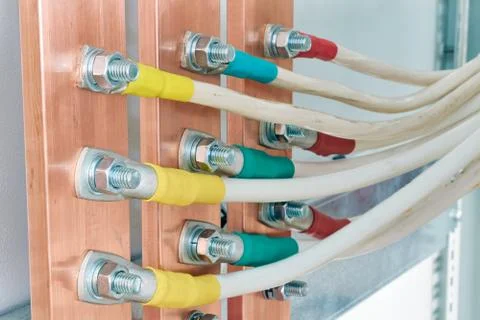 Several flexible electrical cables or wires are attached to copper buses. Stock Photos