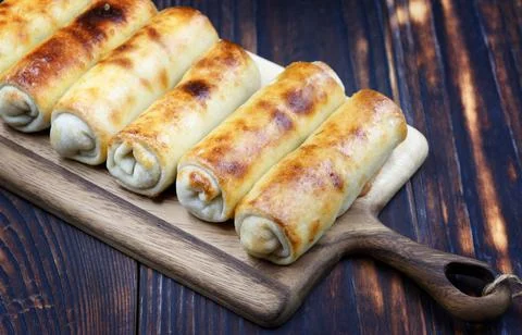Several fried spring rolls lie on a wooden board in a row Stock Photos