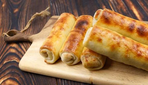 Several fried spring rolls lie on a wooden board in a row Foto stock