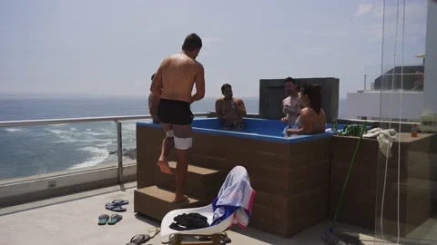 Several friends drinking beer and wine in the pool on the terrace of a beach 動画素材 186234717