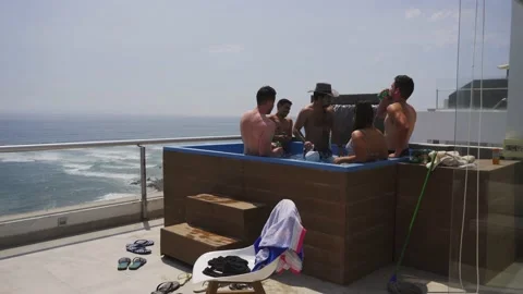 Several friends drinking liquor in the pool of a terrace of a beach house with Stock Footage 189093658