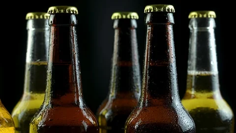 Several full beer bottles stand on a black background Stock Footage 124547866