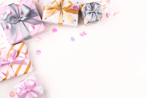 Several gift boxes with bows and confetti on a white background. Stock Photos