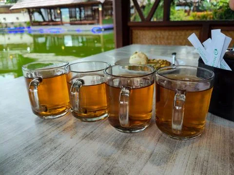 Several glasses of plain tea on the dining table with a pool in the background Stock Photos