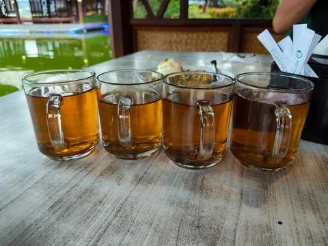 Several glasses of plain tea on the dining table with a pool in the background Stock Photos