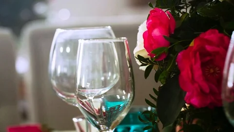 Several glasses for wine surrounded by glasses and plates and flower arrangement Stock Footage 97722118