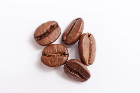Several grains of roasted coffee on a white background. macro. photographed Stock Photos