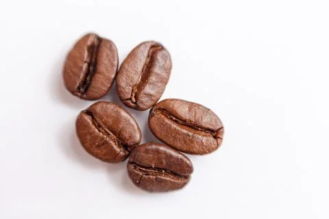 Several grains of roasted coffee on a white background. macro. photographed Stock Photos