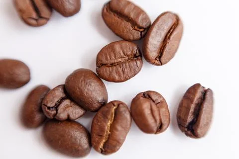 Several grains of roasted coffee on a white background. macro. photographed Stock Photos