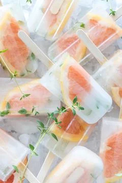 Several grapefruit thyme popsicles piled up on ice. Stock Photos