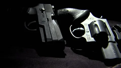 Several guns looking ominous in the shadows as the camera dollies across them.  Stock-Footage 62953433
