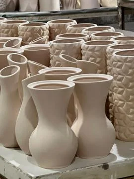Several handcrafted ceramic vases in different designs await firing in a pott Stock Photos