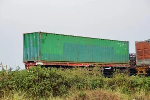 Several interregional cargo container transport trucks parked near a bushy area Stock Photos