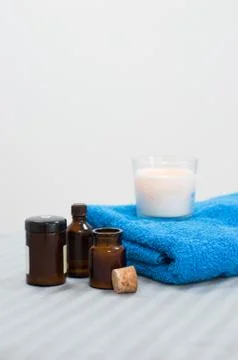 Several jars of essential oils, blue towel and burning candle on white backgr Stock Photos