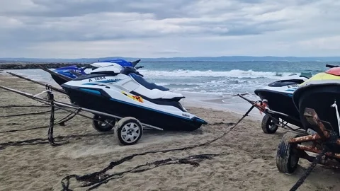 Several jet skis standing on trailers on the beach by the sea Stock Footage 328122059