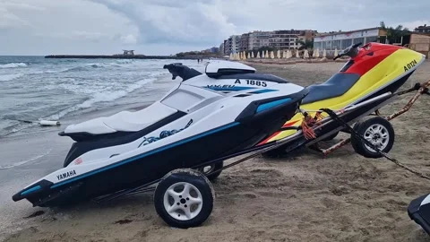 Several jet skis standing on trailers on the beach by the sea Stock Footage 328122062