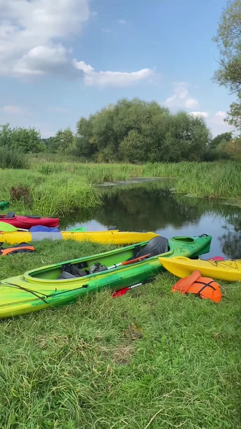 Several kayaks lying on the grass on the river bank. Vertical video Stock Footage 282201037