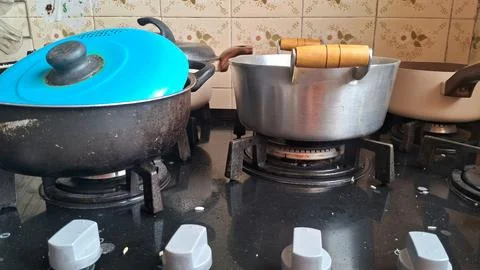Several kitchen pots sitting on a black glass gas stove Stock Photos