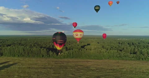 Several large multi-colored vibrant balloons rising against blue sky Stock Footage 158456147