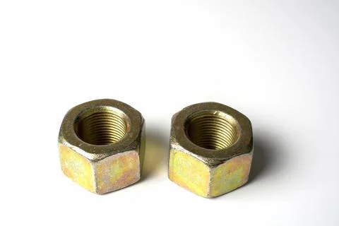 Several large nuts made of yellow metal on a white background Stock Photos