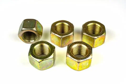Several large nuts made of yellow metal on a white background Stock Photos
