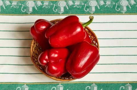 Several large red pepper lie in the wattled plate standing on a towel Stock Photos