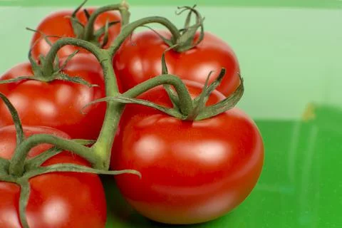 Several large red tomatoes close-up on a green background Foto stock