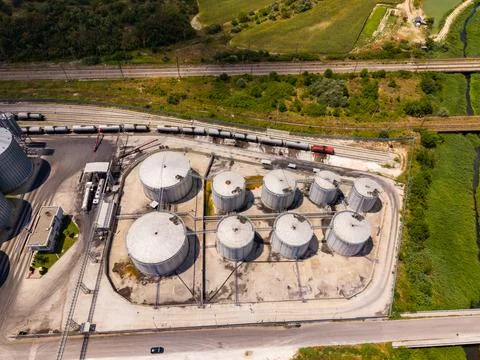 Several large storage tanks are arranged in a circular pattern near train tra Stock Photos