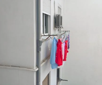 Several lines of hanging clothes in front of window. Clean white facade. Foto stock