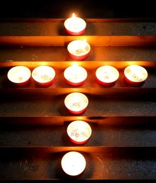 Several luminous devotional candles shaped like a cross spiritual emblem in.. Stock Photos