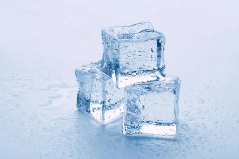 Several melted ice cubes with drops on a light background with blue tinting 스톡 사진