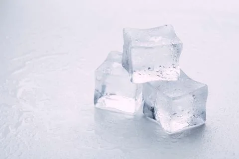 Several melted ice cubes with drops on a light background with blue tinting Foto stock