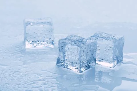 Several melted ice cubes with drops on a light background with blue tinting Stockfoto's