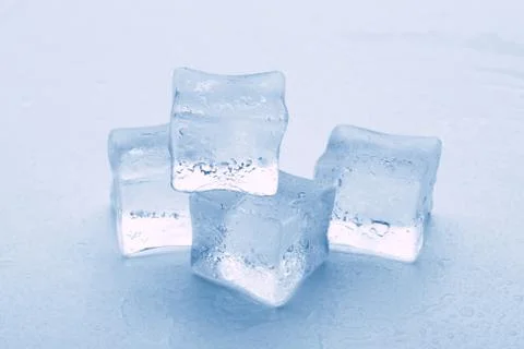 Several melted ice cubes with drops on a light background with blue tinting 스톡 사진