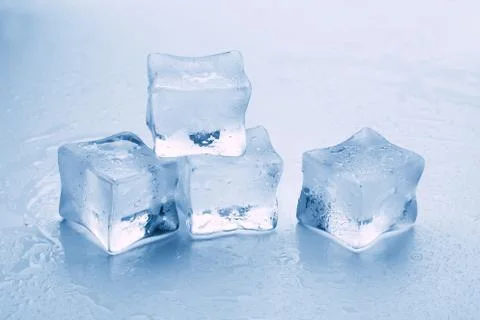 Several melted ice cubes with drops on a light background with blue tinting Stock Photos