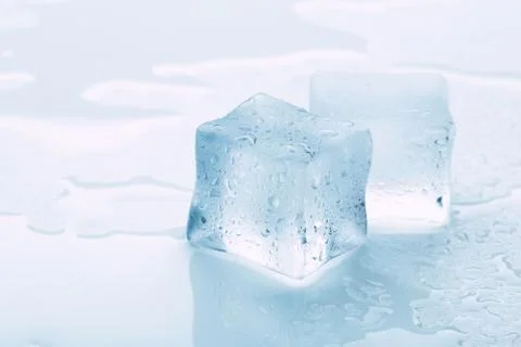 Several melted ice cubes with drops on a light background with blue tinting Foto stock