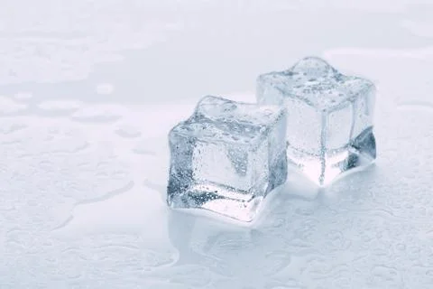 Several melted ice cubes with drops on a light background with blue tinting Foto stock