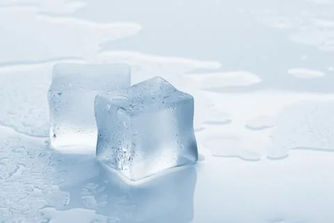 Several melted ice cubes with drops on a light background with blue tinting Stock Photos