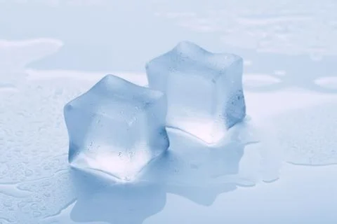 Several melted ice cubes with drops on a light background with blue tinting Foto stock