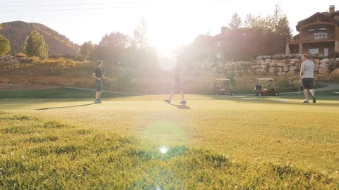 Several men exchange putters on golf course green Stock Footage 102674009