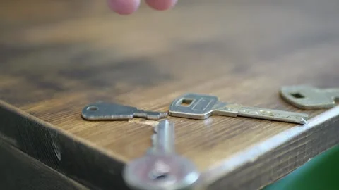 Several metal keys sequentially falling wooden table edge sharp impact sounds Stock Footage 320895303