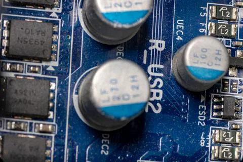 Several microcircuits and transistors on a blue motherboard in a close-up of a Stock Photos