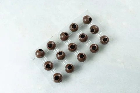 Several milk chocolate shells in the shape of balls inside the mold top view. Stock Photos