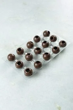 Several milk chocolate shells in the shape of balls inside the mold vertical. Stock Photos