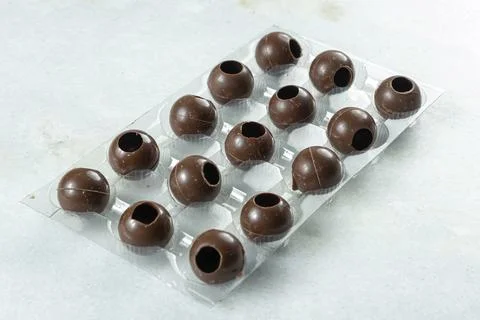 Several milk chocolate shells in the shape of balls inside the mold. Stock Photos